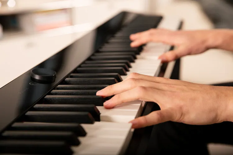 Hands playing a digital piano during a music lesson